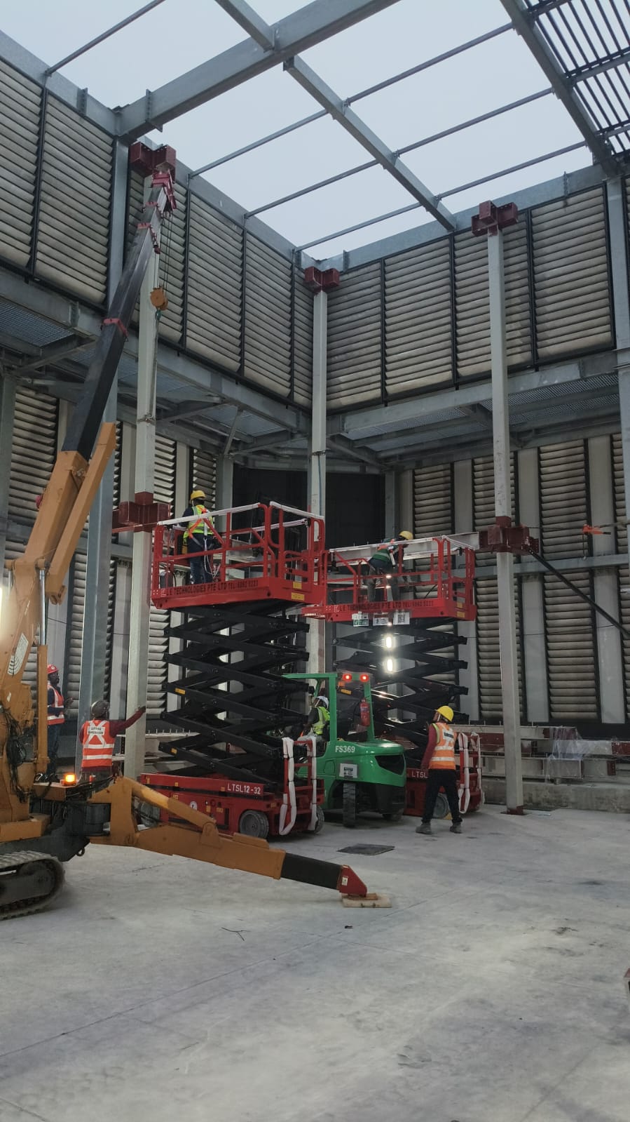 Aerial work crews installing overhead structural cross-bracing with scissor lifts